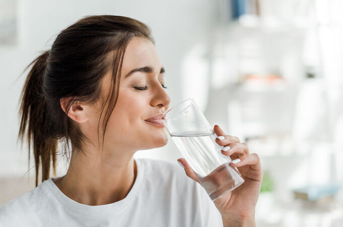 smiling girl holding drinking water from glass in the morning